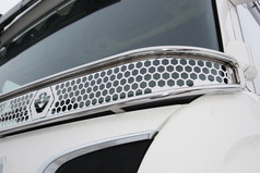 Glnzendes Scheibengitter aus Edelstahl mit Wabenmuster und abgerundeten Kanten an der Frontscheibe eines weien Scania LKW.