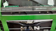 Silbernes Scheibengitter mit Wabenmuster auf der Front eines grnen MAN LKWs.