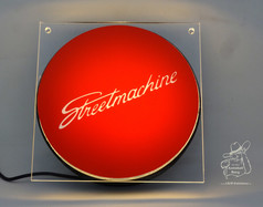 Ein beleuchtetes Schild "Streetmachine" auf einer Acrylplatte, mit USB-Anschluss.