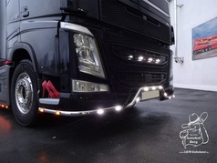 Chrom-Eckrohre mit weien und gelben LEDs an der Stostange eines schwarzen Volvo FH LKW.