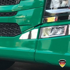 Zweiteilige, spiegelpolierte Edelstahl-Blende 1 an der Front eines grnen Scania LKW.