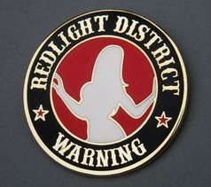 Runder gold-schwarzer Pin mit rotem Kreis, weier Frauensilhouette und "REDLIGHT DISTRICT WARNING" Text.