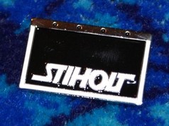 Ein rechteckiger Scandi Pin "Stiholt" mit glnzend schwarzem Feld, weier "STIHOLT" Schrift und silbernem Metallrand.