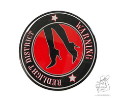 Runder 3D-Aufkleber mit schwarzem Rand, rotem Zentrum, schwarzer Silhouette von Frauenbeinen und dem Text 