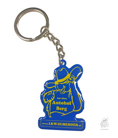 Schlsselanhnger LKW Zubehr: Blauer Anhnger mit gelbem Trucker-Motiv, Text "Am alten Autohof Berg" und "www.LKW-ZUBEHOER.de".