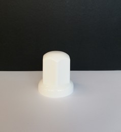 Weie, lange Radmutterkappe aus Kunststoff auf hellem Untergrund.