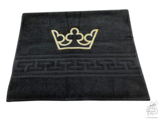 Schwarzes Handtuch mit gold-wei gestickter Krone und geometrischem Musterband.
