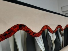 Beige Scheibenbordre aus Wildlederimitat mit schwarzem Klettband und gewellter rot-schwarz gemusterter Plschkante.