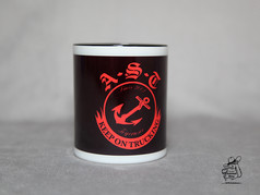 Dunkle Keramiktasse mit weiem Rand und rotem A.S.T. Keep on Trucking Logo mit Anker.