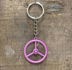 Ein rosa Old School Lenkrad Schlsselanhnger mit silbernem Schlsselring und Kette, auf einer Holzoberflche.