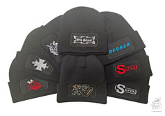 Mehrere schwarze Wintermtzen mit verschiedenen Stickereien im Patchfeld, darunter "Old Skool" und "BESSER".
