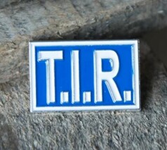 Blauer Scandi Pin mit weier T.I.R. Aufschrift und silbernem Rand.