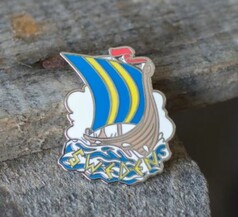 Metallpin mit braunem Wikingerschiff, blau-gelbem Segel und dem Schriftzug SWEDEN auf blauen Wellen.