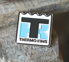 Scandi Pin Thermo King Anstecker. Weier Pin mit gezacktem Rand, schwarzen und hellblauen TK-Buchstaben und THERMO KING Schriftzug.