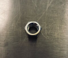 Silberne Mutter fr US Antennen mit Innengewinde auf metallischem Untergrund.