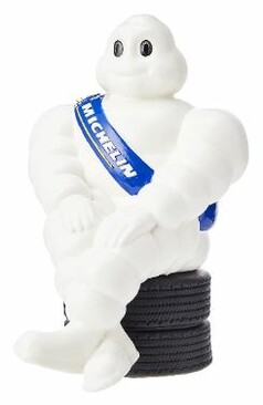 Weies Original Michelin Mnnchen sitzt auf schwarzen Reifen, mit blauer MICHELIN Schrpe.