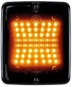Eckige LKW-Heckleuchte mit schwarzem Gehuse und dunkler Linse. Orangefarbene LEDs leuchten als Blinklicht.