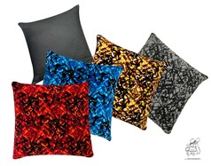 Verschiedene Plschkissen mit abstrakten Mustern in Rot, Blau, Gelb, Grau und ein Kissen mit schwarzer Stoffrckseite.