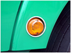 Edelstahl-Blinkereinrahmung am grnen Kotflgel eines LKW mit orangefarbenem Blinker.